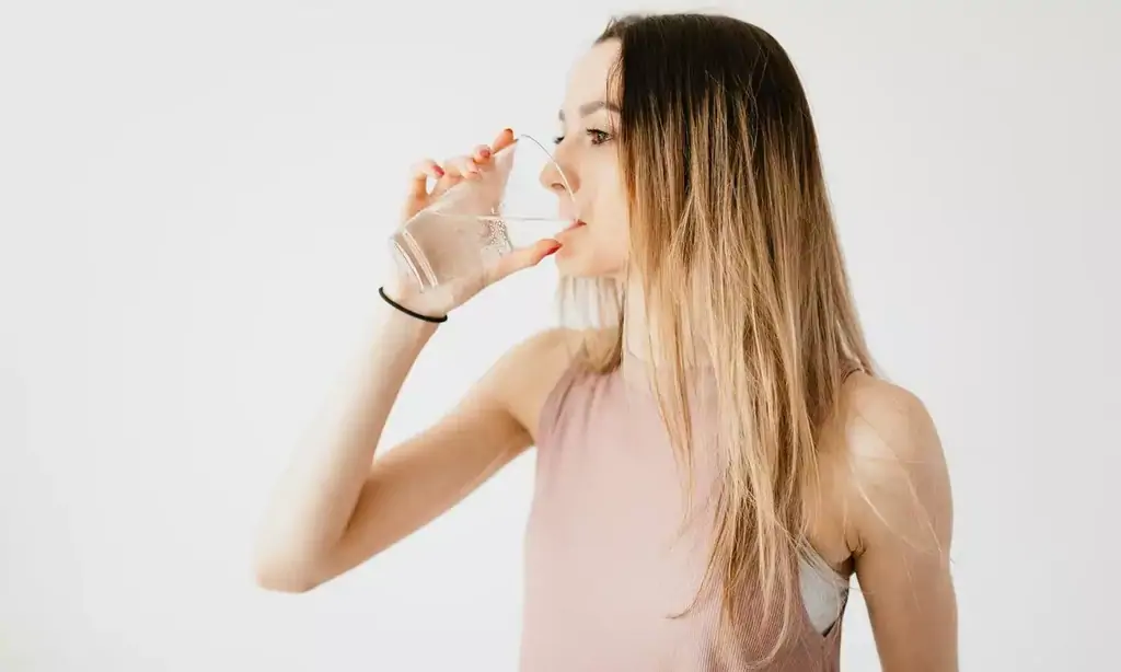 Frau trinkt Wasser mit D-Mannose